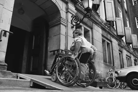 Man in rolstoel gebruikt aangepaste ingang