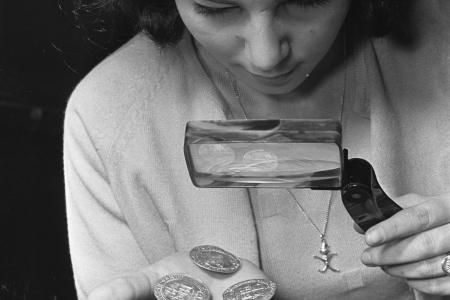 Woman looking at coins through looking glass